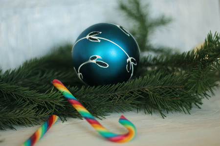 festive decorative blue bauble on christmas tree branch and candy canesの写真素材