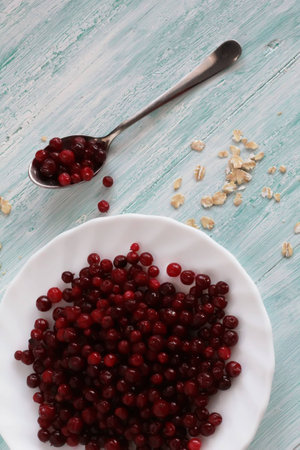 frozen cranberry on wooden background with plate and spoonの写真素材