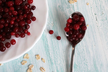 frozen cranberry on wooden background with plate and spoonの写真素材