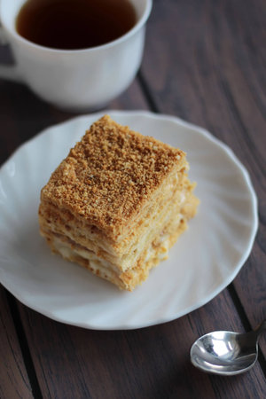Napoleon cake and a cup of tea on dark wooden background