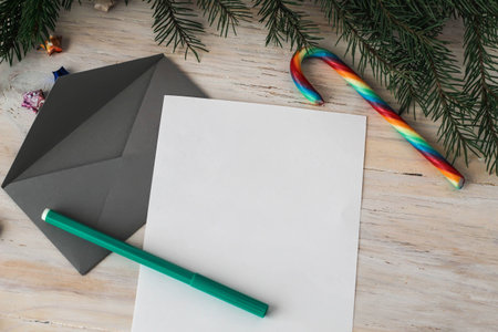 Letter to Santa Claus and grey envelope laid on a wooden table, candy canes, christmas tree