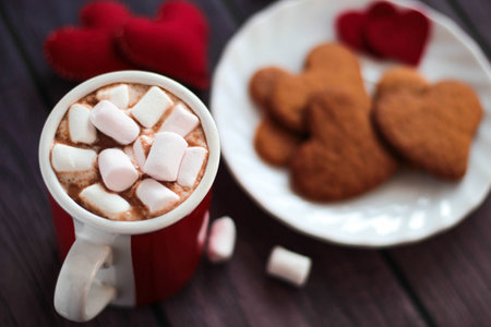 Gingerbread cookies, cup of cocoa with marshmallows and felted hearts on dark wooden background Valentines day Celebration top viewの写真素材