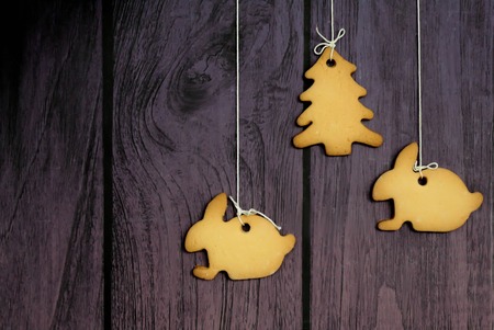 Gingerbread cookies hanging over purple wooden background christmas tree and hare horizontal
