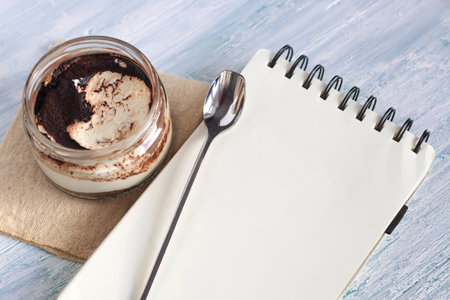 Homemade italian dessert tiramisu in jar with notebook, copy space valentines day place for textの写真素材