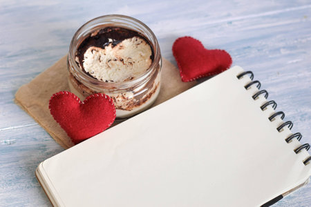 tasty dessert tiramisu in a jar with notebook and red felted hearts top view valentines day place for textの写真素材