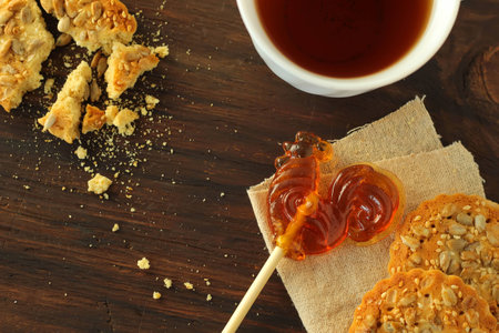 The Time of Tea Break on the table Cookies with sunflower seeds, a cup of tea, lollipop on dark wooden backgroundの写真素材