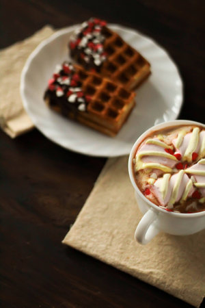 Delicious Belgian waffle with berries, cream and heart shaped topping and hot chocolate with marshmallows for breakfast on dark wooden background. Valentines day celebration concept top viewの写真素材