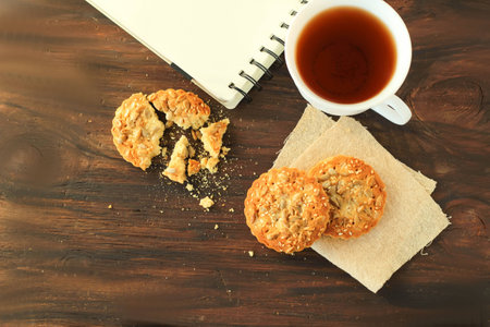 The Time of Tea Break on the table Cookies with sunflower seeds, a cup of tea and notebook on dark wooden background place for textの写真素材