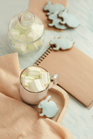 Homemade Colorful easter cookies hare shaped, a cup of hot chocolate and notebook on turquoise...