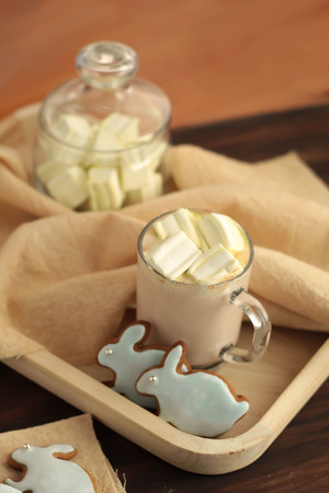 mug full of hot cocoa with marshmallows and hare shaped cookies on a dark background Easter celebrationの写真素材