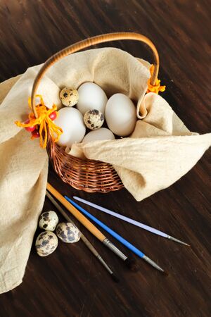 Rustic still life with quail and chicken eggs in a basket ready for decoration on the wooden vintage background for Easterの写真素材