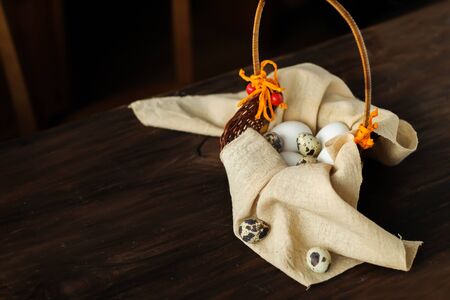Different types of eggs in a basket on a wooden table Easter background place for textの写真素材