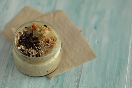 breakfast muesli and chocolate smoothie jar topped with sesame seeds and energy bars on turquoise wooden board healthy vegetarian breakfastの写真素材