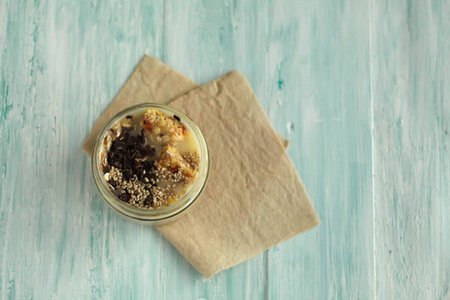 Breakfast smoothie jar topped with chocolate, muesli and sesame seeds. healthy vegan food concept top view place for textの写真素材