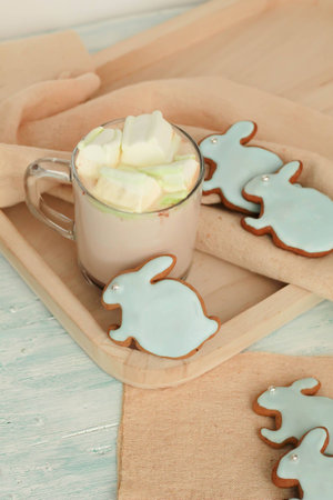 Homemade Colorful easter cookies hare shaped and a cup of hot chocolate on turquoise wooden boardの写真素材