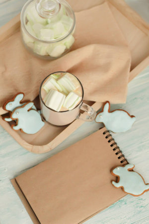 Homemade Colorful easter cookies hare shaped, a cup of hot chocolate and notebook on turquoise wooden board top view place for textの写真素材