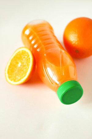 plastic bottle of orange juice and fresh oranges on table. Empty fitness conceptの写真素材