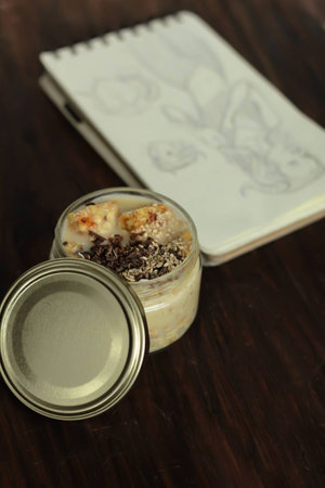 notebook and muesli with yoghurt and chocolate in a jar on wooden table top viewの写真素材