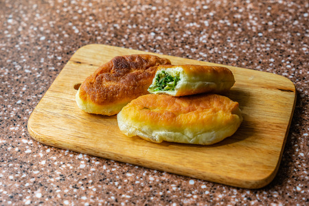 Fresh fried small handmade patties with green onions and egg on a cutting wooden boardの写真素材