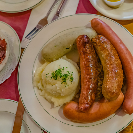 German mixed sausages for beer with mashed potatoes, greens, stewed cabbage and seasonings.の写真素材
