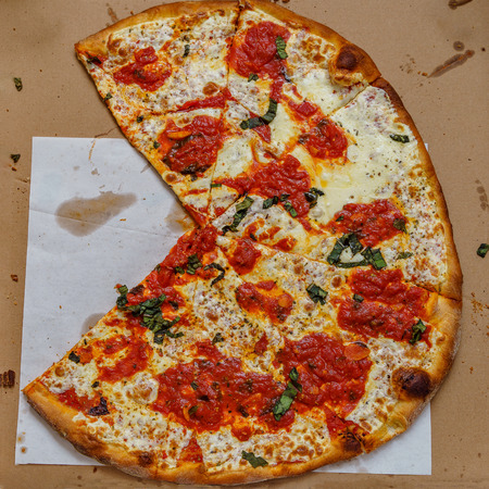 A real tasty cheese pizza from a restaurant on cardboard.の写真素材