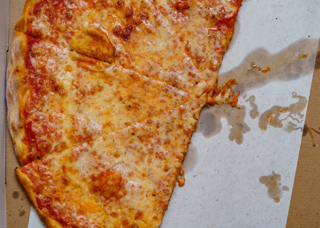 A real tasty cheese pizza from a restaurant on cardboard.の写真素材