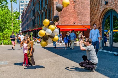 Brooklyn, New York, USA - May 19, 2019: Man taking pictures a girl, maybe a daughter, with an African-American queen with yellow and black balloons, Brooklyn Historical Society DUMBO, St. Anns Warehouseのeditorial素材
