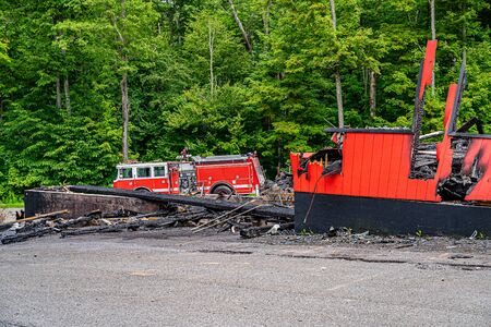 Big red fire truck near the burnt out shop, fire extinguished.の写真素材