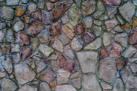 Wall of colored stones fastened with cement, background.の写真素材