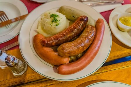 German mixed sausages for beer with mashed potatoes, greens, stewed cabbage and seasonings.の写真素材