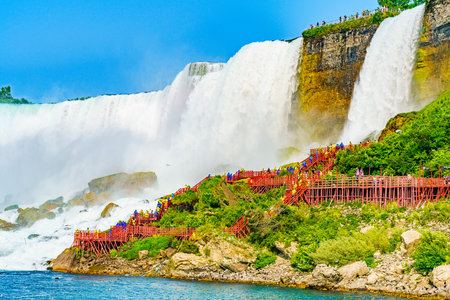 Tourists in raincoats on the Cave of the Winds Lookout, stairs and platforms, wooden walkways, ponchos for an up-close and wet view of the Bridal Veil Falls at the foot of the Niagara Falls, on Goat Island, Niagara Falls, New York, USAの写真素材