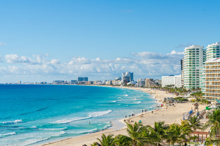 Panoramic view of Cancunâs Hotel Zone with golden sand, turquoise ocean, palm trees, and luxury resorts under a bright blue sky High-quality photoの写真素材