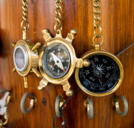 Old bronze compasses are hanging on a chain on a wooden wallの写真素材