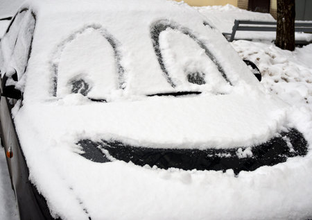 Drawing smiley face on the snow-covered carの写真素材