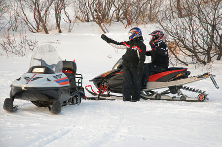 Murmansk, Russia - February 15, 2010: The driver of a snowmobile indicates the way to another friendのeditorial素材