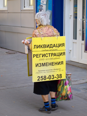 Voronezh, Russia - June 5, 2013: A pensioner carries an advertising posterのeditorial素材