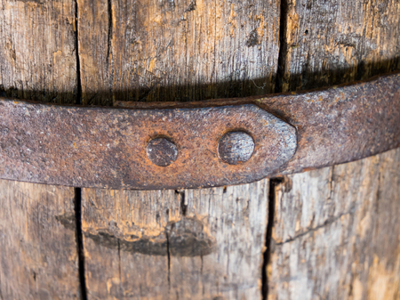 Fragment of a riveted metal hoop on an old wooden barrelの写真素材