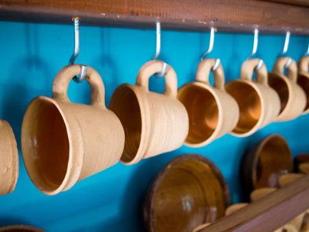 A number of clay mugs dry on the shelf of a pottery workshop