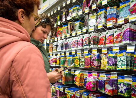 Voronezh, Russia - October 14, 2018: Women choose flower seeds while standing at the sample caseのeditorial素材