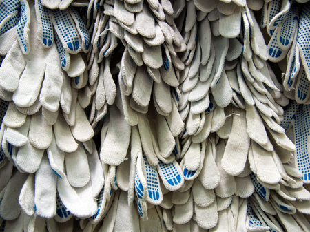 Many cloth work gloves hang on the rack