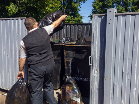 Lipetsk, Russia - June 10, 2018: A man throws plastic bags with garbage in a containerのeditorial素材