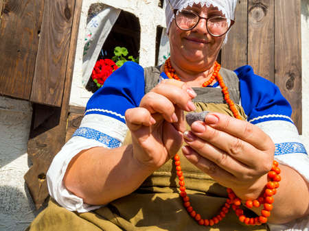 Voronezh, Russia - September 5, 2019: Woman in national costume makes toy from felted woolのeditorial素材