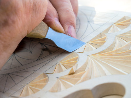 Woodcarver knife creates a geometric pattern on a wooden board.