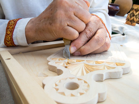 Master carver decorates a wooden board with a pattern