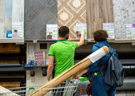 Voronezh, Russia - Juny 26, 2020: Shop consultant helps the buyer in choosing linoleumのeditorial素材