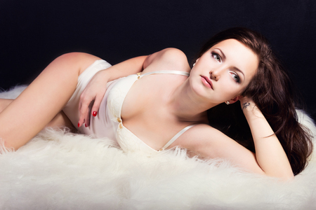 beautiful young sexy girl brunette with makeup in the white bodysuit in the Studio on a black backgroundの写真素材