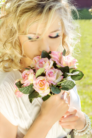 young beautiful elegant, attractive girl blonde with long hair in a Sunny day c a makeup blue eyes in a white dress with a smile on your faceの写真素材