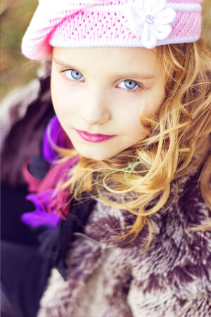 little girl with blue eyes in the pink hat sitting in the forestの写真素材