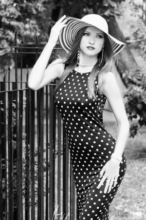 sexy girl with red lips in the hat dress with polka dots standing around outside in the Park on a Sunny summer dayの写真素材