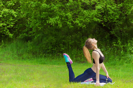 beautiful young girl is engaged in sports, yoga, fitness on the beach by the river on a Sunny summer dayの写真素材